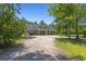 Wide exterior shot of the home with an extended front porch surrounded by mature trees and a gravel driveway at 140 Pixie Dust Ct., Myrtle Beach, SC 29588