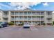Condo building exterior with balconies, ample parking and manicured landscaping on a partly cloudy day at 1450 St. George Ln. # E, Myrtle Beach, SC 29588