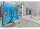 Bathroom featuring a vibrant tropical shower curtain, white vanity, mirror and storage shelves at 155 Palmetto Green Dr., Longs, SC 29568