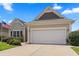 Beige single-story home with an attached two-car garage, complemented by an American flag at 155 Palmetto Green Dr., Longs, SC 29568