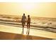 Couple enjoying a peaceful walk on a sandy beach, with calm waves and a golden sunset creating a serene atmosphere at 222 Atlantic Breeze St., Myrtle Beach, SC 29572