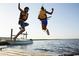 Image captures a dynamic scene of children leaping from a dock into the water on a sunny day at 222 Atlantic Breeze St., Myrtle Beach, SC 29572