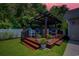 Cozy outdoor kitchen and seating area with green lawn and ambient lighting at 2479 Burning Tree Ln., Little River, SC 29566