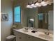 Bathroom featuring a double vanity, well-lit mirror, tiled shower, and a toilet near a window at 312 Shelly Bay Ct., Surfside Beach, SC 29575