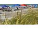 Beach scene with vegetation in the foreground and blue and orange umbrellas at 312 Shelly Bay Ct., Surfside Beach, SC 29575