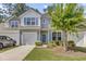 Charming two-story home featuring a garage, blue shutters, and a well-manicured lawn with a beautiful flowering tree at 315 Bulkhead Bend # 315, Carolina Shores, NC 28467