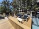 An outdoor deck area features white patio furniture and overlooks beautiful landscaping for peaceful relaxation and enjoyment of the outdoors at 4800 S Ocean Blvd. # 706, North Myrtle Beach, SC 29582
