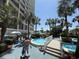 Poolside view of a modern resort with beautiful pools, palm trees, walkways, and sunbathers at 4800 S Ocean Blvd. # 706, North Myrtle Beach, SC 29582