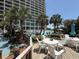 Pool deck with white tables and chairs and palm trees near the resort building at 4800 S Ocean Blvd. # 706, North Myrtle Beach, SC 29582