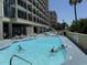 View of a large pool with people swimming and lounge chairs and the resort buildings in the background at 4800 S Ocean Blvd. # 706, North Myrtle Beach, SC 29582