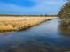 Scenic view of a marsh landscape with tall grasses and a calm waterway under a clear blue sky at 52 Trimmings Ct., Pawleys Island, SC 29585