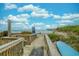 Scenic beach access with a wooden boardwalk, dunes, and a clear view of the ocean and pier under a partly cloudy sky at 6001 N Ocean Blvd. # 137, North Myrtle Beach, SC 29582