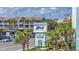 Exterior view of Monterey Bay Suites sign with palm trees and the building in the background at 6804 North Ocean Blvd. # 515, Myrtle Beach, SC 29572