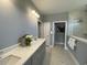 Bright bathroom with a double vanity, gray cabinets, white countertop, and marble-lined shower at 121 Eagle Claw Dr., Carolina Shores, SC 28467