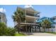Three-story beach house on stilts with double balconies and tropical landscaping at 221 N Waccamaw Dr., Murrells Inlet, SC 29576