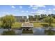 Elevated view of a dock extending into a pond, framed by trees, clubhouse, and lush grass at 4051 Mclamb Ave. # 4051, Little River, SC 29566