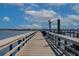 Scenic view down a wooden pier towards the ocean and coastline under a blue sky at 4539 Fringetree Dr., Murrells Inlet, SC 29576