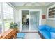 Bright sunroom with tile flooring, blue sofa, and view to office space at 654 Blue Bird Ln., Murrells Inlet, SC 29576