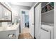 Well-lit bathroom featuring a double sink vanity, laundry closet, and neutral tile flooring at 7700 Porcher Dr. # 3207, Myrtle Beach, SC 29572