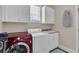 Well-lit laundry room with white cabinets, sink and a modern red washing machine at 8013 Wacobee Dr., Myrtle Beach, SC 29579