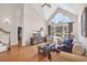 Bright living room featuring hardwood floors, a high vaulted ceiling, and large windows with views of lush greenery at 8013 Wacobee Dr., Myrtle Beach, SC 29579