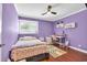 A purple bedroom featuring a window, ceiling fan, bed, desk and chair, and wood flooring at 10301 North Kings Hwy. # 21-4, Myrtle Beach, SC 29572