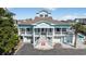 Stunning coastal home featuring a two-story design, complemented by white railing, and manicured landscaping at 1885 Pompano Dr., Garden City Beach, SC 29576
