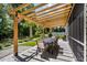 Outdoor dining and grilling area under a wooden pergola with seating, surrounded by lush landscaping at 216 Palm Terrace Loop, Conway, SC 29526
