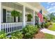 Inviting front porch with hanging ferns, an American flag, and a cozy seating area at 226 Red Tail Hawk Loop, Pawleys Island, SC 29585