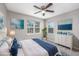 This bedroom features neutral decor, two windows, and pops of blue in bedding and art, creating a serene retreat at 4490 Barcelona Ln., Little River, SC 29566