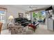 Comfortable living room with a black leather sofa and access to a screened balcony overlooking greenery at 493 White River Dr. # 28-D, Myrtle Beach, SC 29579