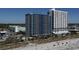 Expansive beachfront view of tall condominium complex overlooking sandy beach with blue skies at 504 Ocean Blvd. N # 410, Myrtle Beach, SC 29577