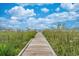 Wooden boardwalk leading to the beach with blue skies and beach umbrellas in the distance at 5511 N Ocean Blvd. # 902, Myrtle Beach, SC 29577