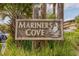 Mariners Cove sign with pelican artwork, tropical foliage and building in background, indicating a welcoming community at 9501 Shore Dr. # B-224, Myrtle Beach, SC 29572