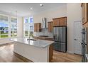 Bright kitchen featuring an island, stainless steel appliances, wood cabinetry, and large windows at 1228 Colusa Ct., Little River, SC 29566