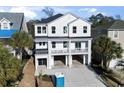 Aerial of a white three-story home with a two-car garage and large driveway at 410 5Th Ave. S, North Myrtle Beach, SC 29582