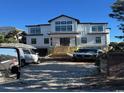 Striking three-story home with white siding and black trim, complemented by a spacious driveway and picturesque surroundings at 4300 N Ocean Blvd., Myrtle Beach, SC 29577
