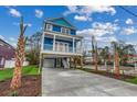 Stilt home features blue siding, white trim, and a covered parking area with palm trees at 721 10Th Ave. S, Surfside Beach, SC 29575