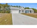 View of single-story home with gray siding, a well-manicured lawn, and a long concrete driveway at 397 Sun Colony Blvd., Longs, SC 29568