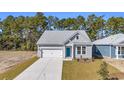 An eye-level side view of a charming single-story home with gray siding and a blue door at 397 Sun Colony Blvd., Longs, SC 29568