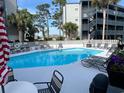 Inviting outdoor pool area has lounge chairs and umbrellas for relaxing by the refreshing water at 1500 Cenith Dr. # F103, North Myrtle Beach, SC 29582