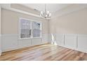Light-filled dining room boasts classic wainscoting, stylish chandelier, and wood-look floors at 623 Carter Reid Ct., Longs, SC 29568