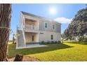 Backyard view of the two-story home with a covered patio, stairs, and lush green lawn on a sunny day at 132 Oak Bay Dr., Georgetown, SC 29440