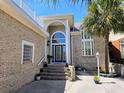 Elegant home exterior featuring a grand entrance with brickwork, large windows and stone stairway at 144 Waterway Crossing Ct., Little River, SC 29566