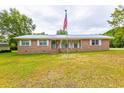Charming brick home featuring an American flag, well-maintained lawn, and a classic design at 705 White Oak Dr., Johnsonville, SC 29555