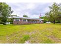 Traditional single-story brick home with a metal roof, a well-maintained lawn, and mature trees in the yard at 705 White Oak Dr., Johnsonville, SC 29555