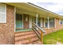 A welcoming front porch with brick steps and green mat, leading to the front door of this charming home at 705 White Oak Dr., Johnsonville, SC 29555