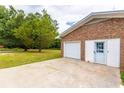 Attached garage and door to backyard, beside cracked driveway and stop sign on the curb at 705 White Oak Dr., Johnsonville, SC 29555