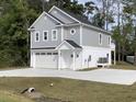 Side view of a two-story gray home with a garage and balcony, surrounded by lush greenery and a long driveway at 1738 Cenith Dr., North Myrtle Beach, SC 29582