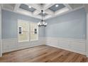 Chic dining area with coffered ceiling, wainscoting, modern chandelier, and large windows enhancing bright and airy ambiance at 219 West Palms Dr., Myrtle Beach, SC 29579
